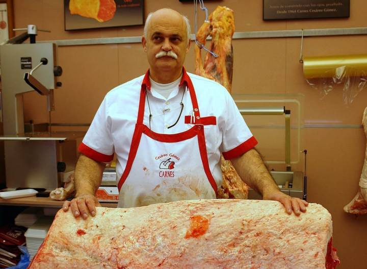 Manolo, carnicero de Cesáreo Gómez, con una pieza de lomo de cebón.