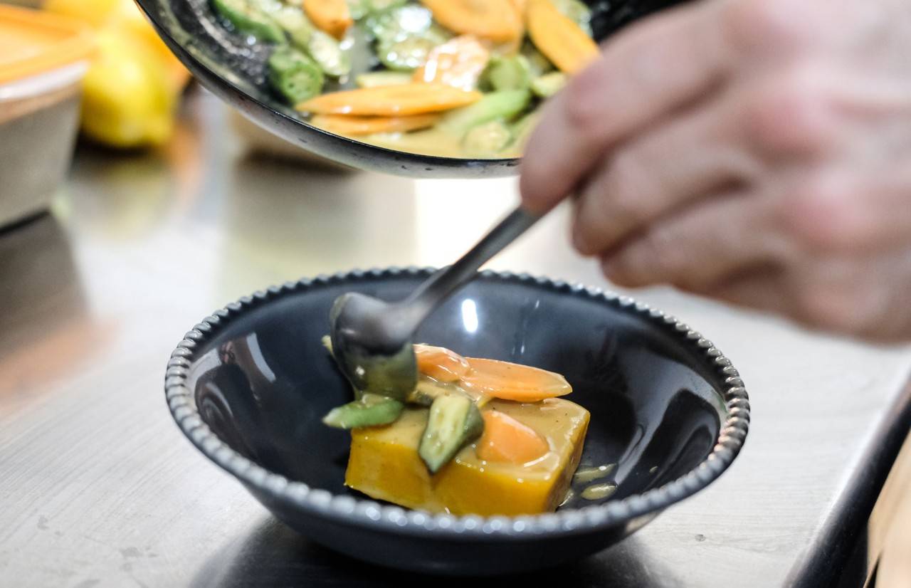 Nacho emplatando el curri verde con verduras del huerto.